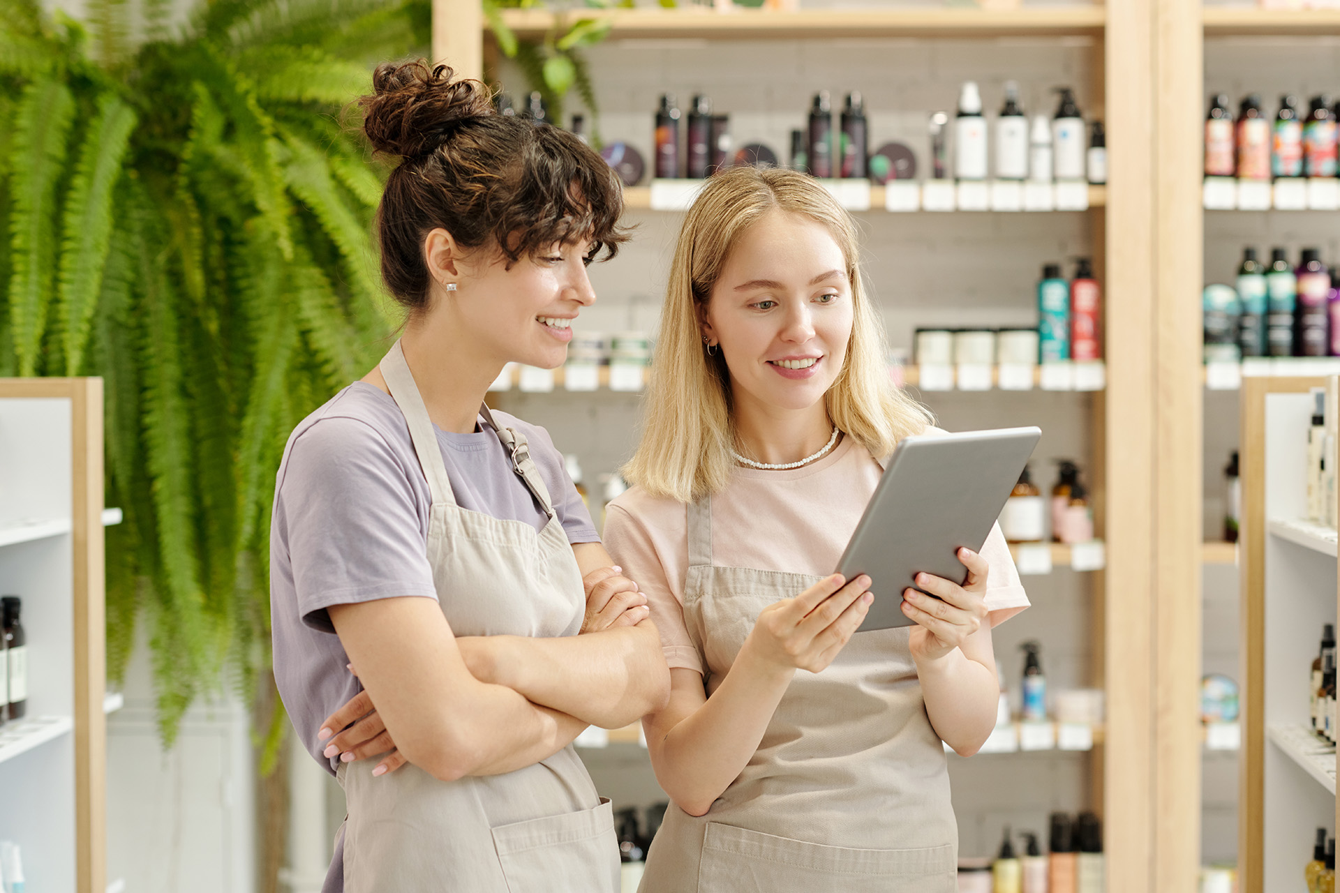 Zwei junge Mitarbeiterinnen eines Beauty-Salons betreiben Inventur und tragen die Ergebnisse auf einem Tablet ein.